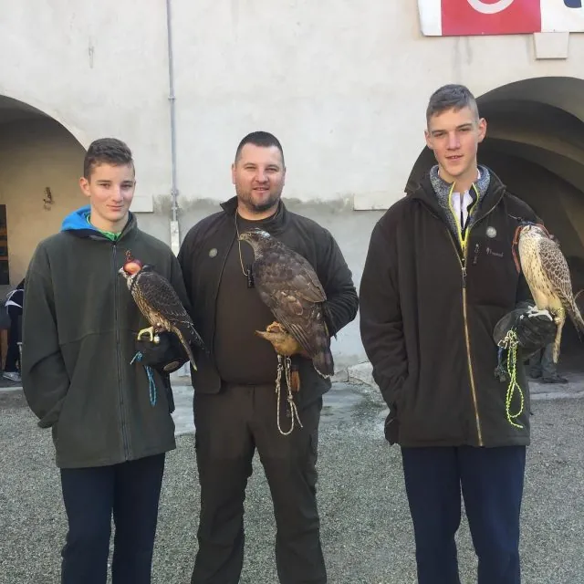 Three falconers in green hunting clothes, each with a falcon on the fist