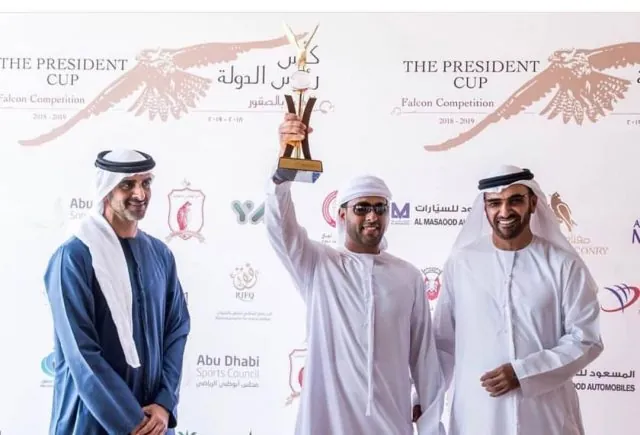 Three men on a podium lifting a gold trophy at the President's Cup